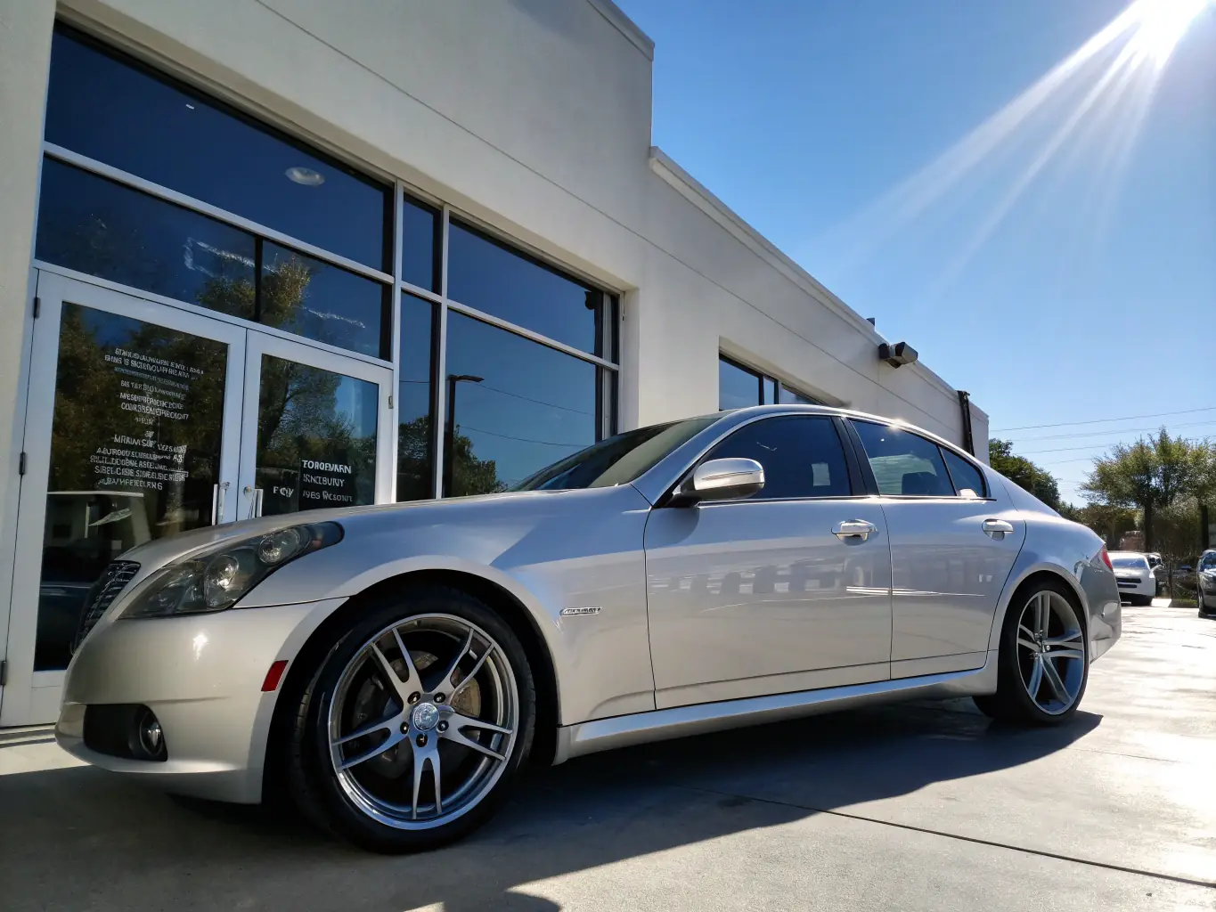 A sleek, modern luxury sedan parked in front of a high-end dealership, representing the luxury vehicle category offered by Delta Cars.